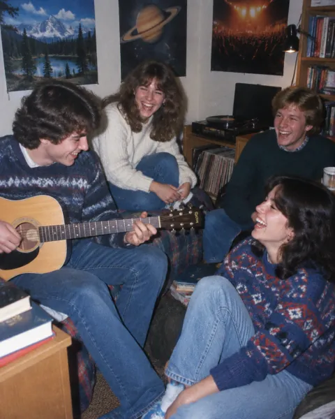 College friends play guitar in a dorm room