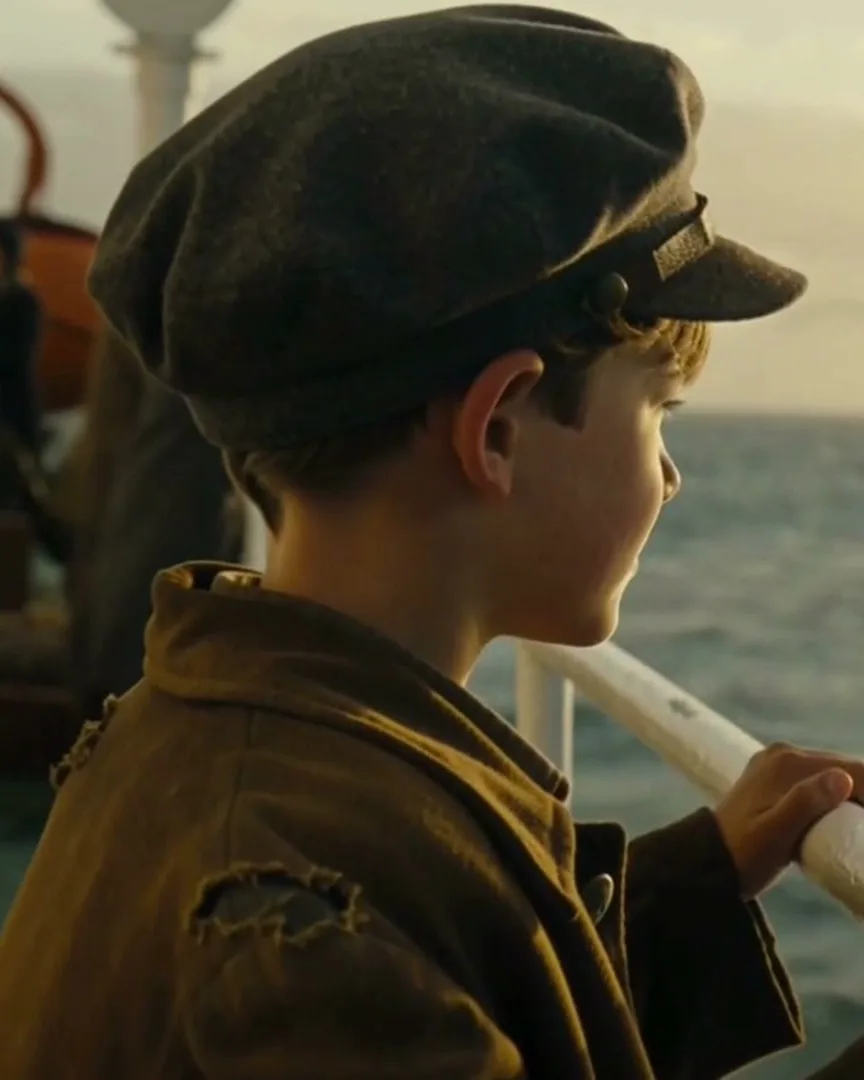 Documentary still: a boy looks out to sea from a ship's rail.